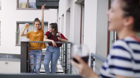 Handheld-video-of-three-friends-having-home-party-on-balcony