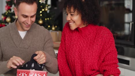 Handheld-view-of-happy-couple-opening-Christmas-gift