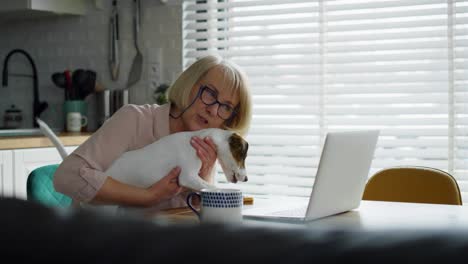 Video-Einer-älteren-Frau-Mit-Hund,-Die-Zu-Hause-Einen-Laptop-Benutzt