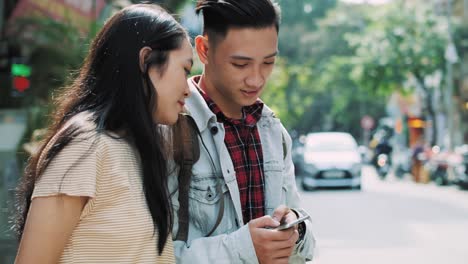 Handheld-view-of-Vietnamese-couple-looking-at-mobile-phone