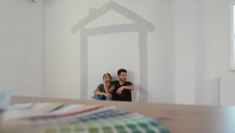 Caucasian-couple-resting-after-wall-painting-of-the-new-house