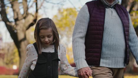 Caucasian-little-girl-walking-with-grandfather-in-the-park