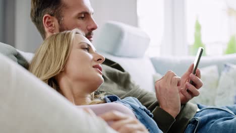 Bored-couple-using-mobile-phone-and-lying-on-sofa