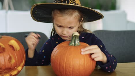 Girl-in-halloween-costume-drawing-on-pumpkin