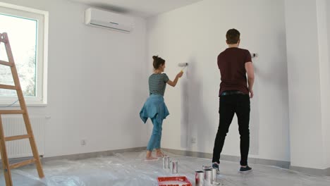 Young-caucasian-couple-painting-house-shape-on-wall-in-new-house