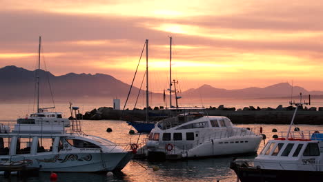 Whale-watching-vessels-bobbing-in-New-Harbour,-Hermanus,-sunrise-golden-sky