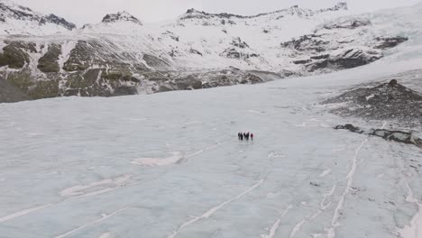 Aerial-panoramic-landscape-view-over-people-hiking-on-the-ice-surface-of-Virkisjokull-glacier,-Iceland