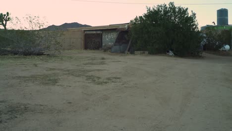 Experience-the-allure-of-the-open-road-in-this-cinematic-clip-captures-as-a-lone-adventurer-arrives-at-an-enchanting-old-farm-in-the-heart-of-the-desert,-riding-a-vintage-chopper-motorcycle
