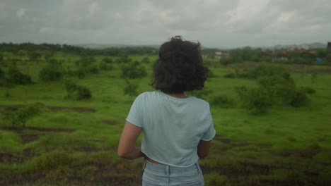 An-Indian-woman-gazes-at-the-vast-expanse-of-the-lush-Indian-forest-her-hair-gracefully-swaying-in-the-gentle-breeze