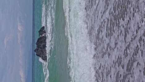 Vertikale-Aufnahme-Des-Strandes-Von-Banbanon-In-Zeitlupe-Mit-Wellen,-Die-über-Die-Sandige-Küste-Rollen