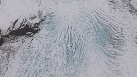 Aerial-view-over-ice-cracks-and-formations-in-Virkisjokull-glacier-covered-in-snow,-Iceland