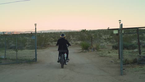 Come-along-on-the-open-road-in-this-cinematic-clip-captures-as-a-lone-adventurer-arrives-at-an-enchanting-old-farm-in-the-heart-of-the-desert,-riding-a-vintage-chopper-motorcycle