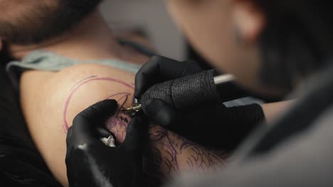 Close-up-of-female-artist-tattooing-arms-of-her-customer.