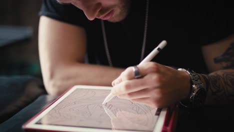 Primer-Plano-De-Un-Tatuador-Caucásico-Diseñando-Motivos-En-Una-Tableta-Digital.
