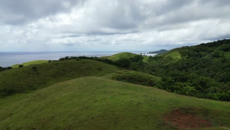 Scenic-aerial-view-of-idyllic-green-hills-and-lush-rainforests-with-stunning-cloudscape-in-Catanduanes,-Philippines