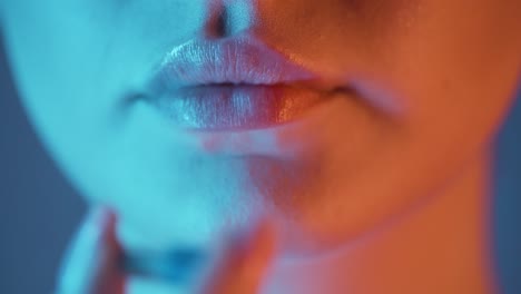 Extreme-close-up-of-a-beautiful-woman-lip-while-she-takes-a-capsule-in-nightlife-to-stay-fit-and-fight-nausea-from-alcohol-for-the-evening-in-club-in-slow-motion-with-blue-and-orange-contrast-in-face