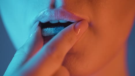 Extreme-close-up-of-a-beautiful-woman-lip-while-she-takes-a-capsule-in-nightlife-to-stay-fit-for-the-evening-in-the-club-in-slow-motion