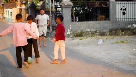 Lindos-Niños-Pequeños-Jugando-Al-Fútbol-Juntos-En-La-Calle-De-Un-Complejo-Residencial-En-Indonesia-En-Verano-Al-Aire-Libre