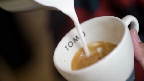 Professional-barista-pouring-latte-foame-over-coffee,-espresso-and-creating-a-perfect-cappuccino