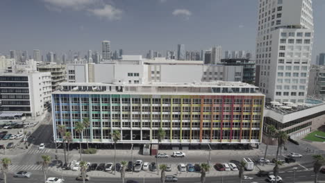 The-colorful-Dan-Hotel-in-Tel-Aviv,-Rainbow-building-on-the-Gordon-promenade-and-Frishman-beach-full-of-visitors-on-a-warm-and-calm-summer-day