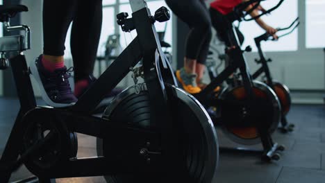 Group-of-smiling-friends-women-class-exercising,-training,-spin-on-stationary-bike-at-modern-gym