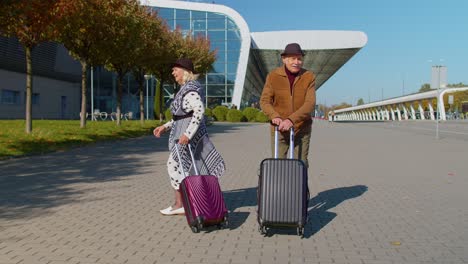 Family-grandmother-grandfather-walking-with-luggage-suitcase-bags-to-airport-hall,-celebrate-dancing