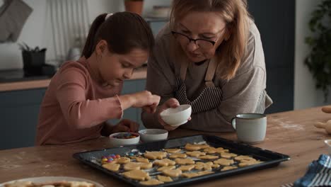 Caucasian-girl-decorating-homemade-cookies-with-grandmother