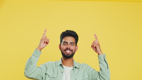 Young-man-showing-thumbs-up-and-pointing-overhead-on-blank-space-place-for-your-advertisement-logo