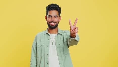 Happy-smiling-Indian-young-man-showing-victory-sign,-hoping-for-success-and-win,-doing-peace-gesture