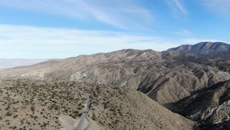 Scenic-road-surrounded-by-deserted-mountains,-Cahuilla-Indian-Reservation-wild-landscape,-California,-USA,-Drone-shot