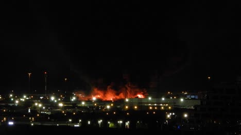 Static-shot-of-a-chemical-plant-up-in-flames-with-smoke-billowing-out-at-night