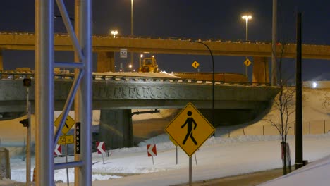 Schneepflug-Arbeitet-Nachts-Auf-Der-Autobahnüberführung,-Um-Schnee-Zu-Räumen,-Montreal,-Kanada