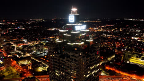 Toma-Aérea-En-órbita-De-La-Iluminación-Del-Rascacielos-Truist-Plaza-Por-La-Noche-En-El-Centro-De-La-Ciudad-De-Atlanta,-Georgia