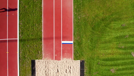 Aerial-top-down---running-track-leading-to-the-long-jump-sandpit-at-an-athletics-stadium