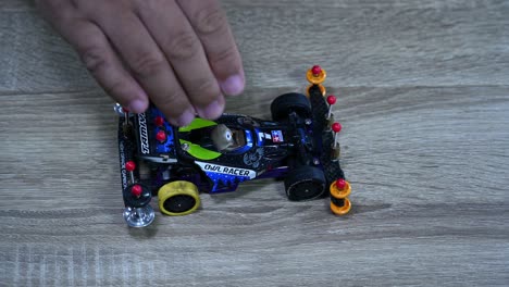 Dropping-a-Tamiya-Mini-sports-car-many-times-on-a-table-inside-a-shop-a-toy-store-in-Bangkok,-Thailand-to-check-its-stability-and-balance