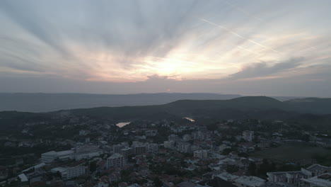 Droneshot-from-above-Kruje-Albania-flying-over-the-city-on-the-cliff-on-a-cloudy-day-with-clouds-against-the-mountains-during-sunset-LOG