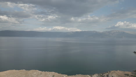 Drone-flying-backwards-over-the-sea-on-a-cloudy-day-with-a-view-on-Macedonia-revealing-the-town-of-Lin-Albania-LOG