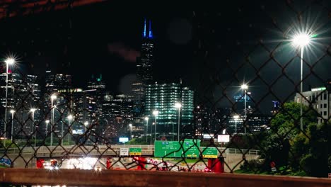 Timelapse-of-Chicago-urban-city-trough-metal-grid-fence-at-night
