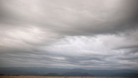 Espectaculares-Nubes-Con-Textura-Gris-Y-Blanca-Repartidas-Por-Llanuras-Cubiertas-De-Hierba,-Panorámica-Hacia-Abajo