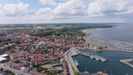 Aerial-forward-over-the-beautiful-port-city-Simrishamn-in-Sweden,-summer-day