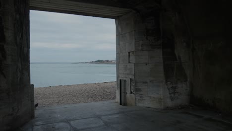 Pigeon-walks-through-the-entrance-of-a-seaside-tower-with-the-ocean-in-the-background