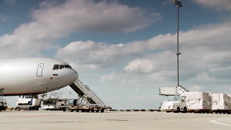 Daylight-airport-scene---Airplane-stands-still-and-crew-transports-cargo