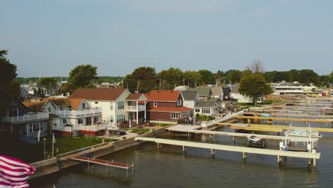 Drone-shot-of-the-beach-houses-and-docks-and-boats-and-flags-at-Sodus-point-New-York-vacation-spot-at-the-tip-of-land-on-the-banks-of-Lake-Ontario