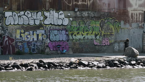 Mann-Fotografiert-Graffitiwand-Entlang-Der-Uferpromenade-Von-Brooklyn,-New-York