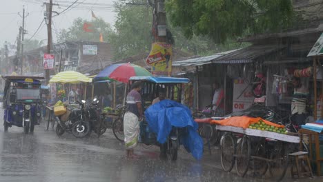 Traffic-across-the-streets-of-rural-Indian-town-in-heavy-rainfall-after-intense-heat-wave-in-the-summer,-Wide-Angle-Shot