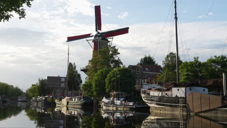 Scenic-View-Of-Windmill-de-Roode-Leeuw-At-Turfsingel-With-Anchored-Vintage-Boats-In-Gouda,-Netherlands