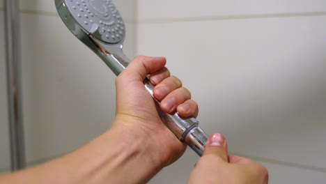 Male-hands-installing-new-flat-shower-head-in-bathroom,-closeup