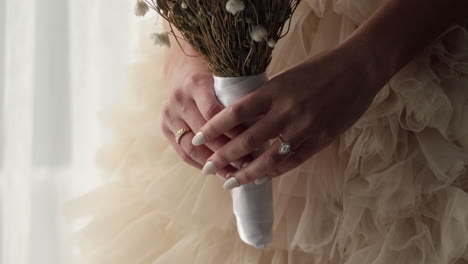 Die-Hände-Der-Braut-Halten-Einen-Blumenstrauß-Mit-Gelnägeln-Und-Diamantringen