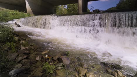 Crashing-Water-over-Edge-of-River,-Bridge-above,-Jasper-Indiana