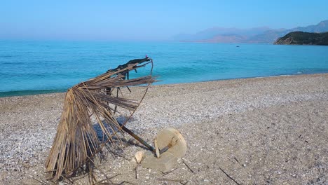 End-of-Summer-Season:-Abandoned-and-Damaged-Straw-Umbrella-on-an-Empty-Beach,-Symbolizing-the-Season's-Conclusion